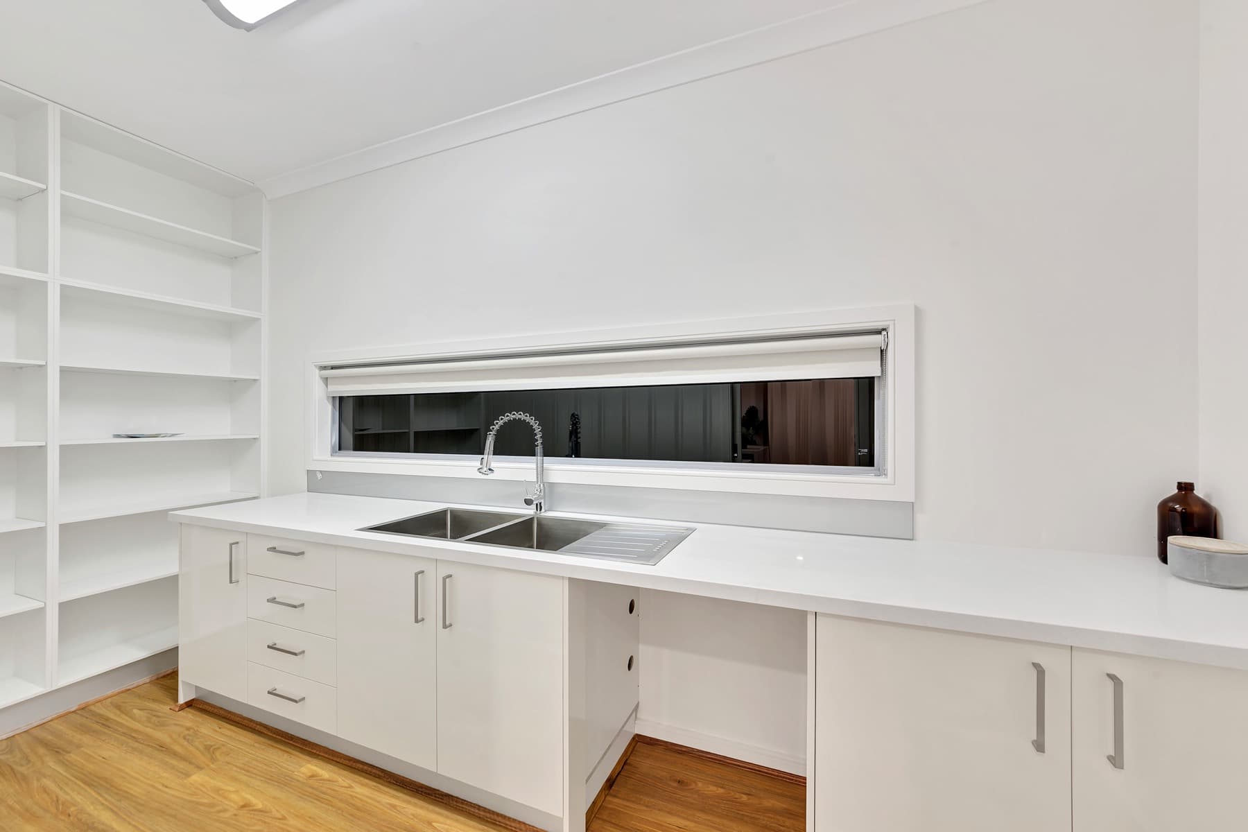 White cabinetry and the sink beneath a slot window