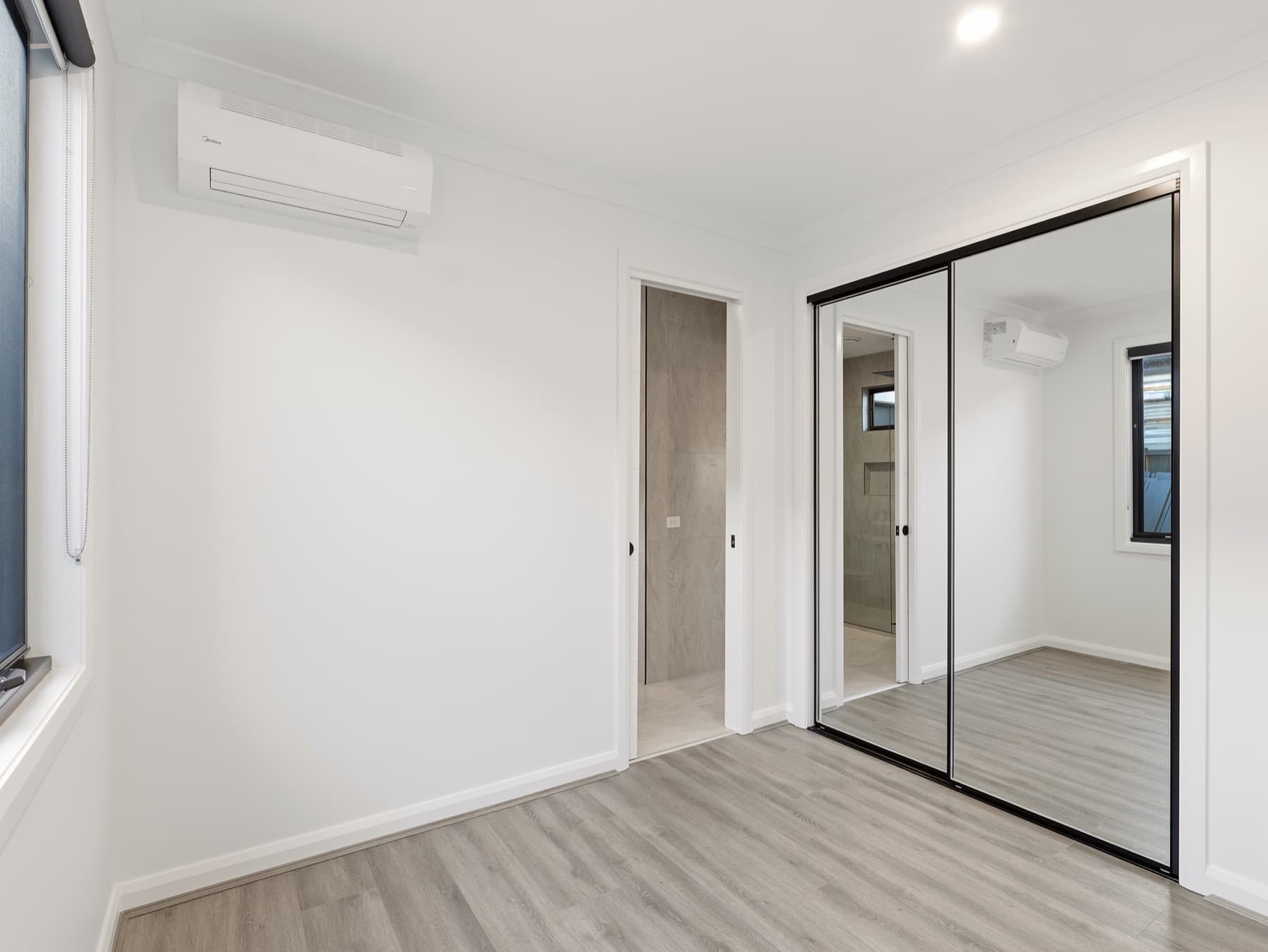 A bedroom with mirrored robes in black frames