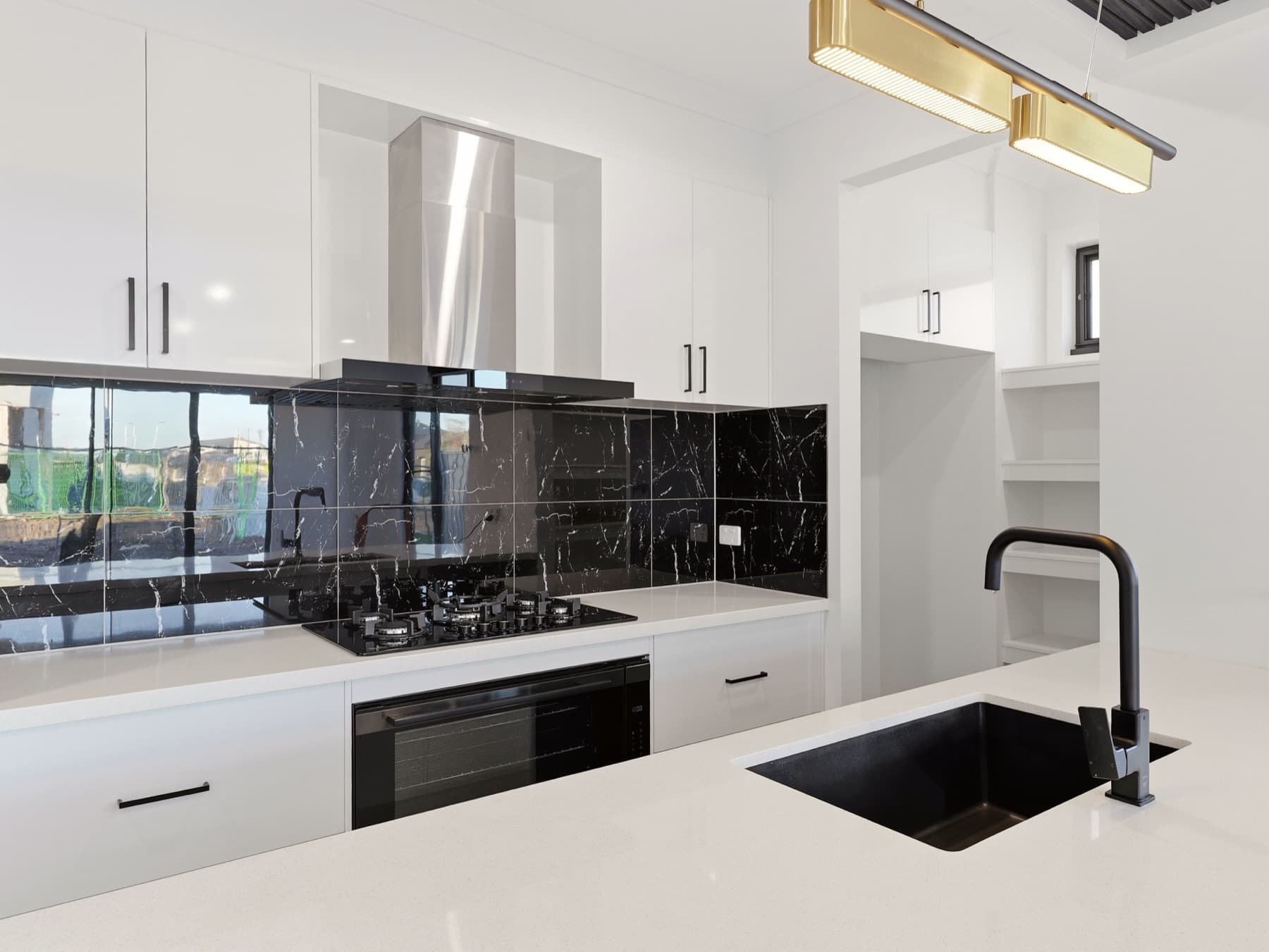 Kitchen of a completed Zaman home, stone island and black marble splashback
