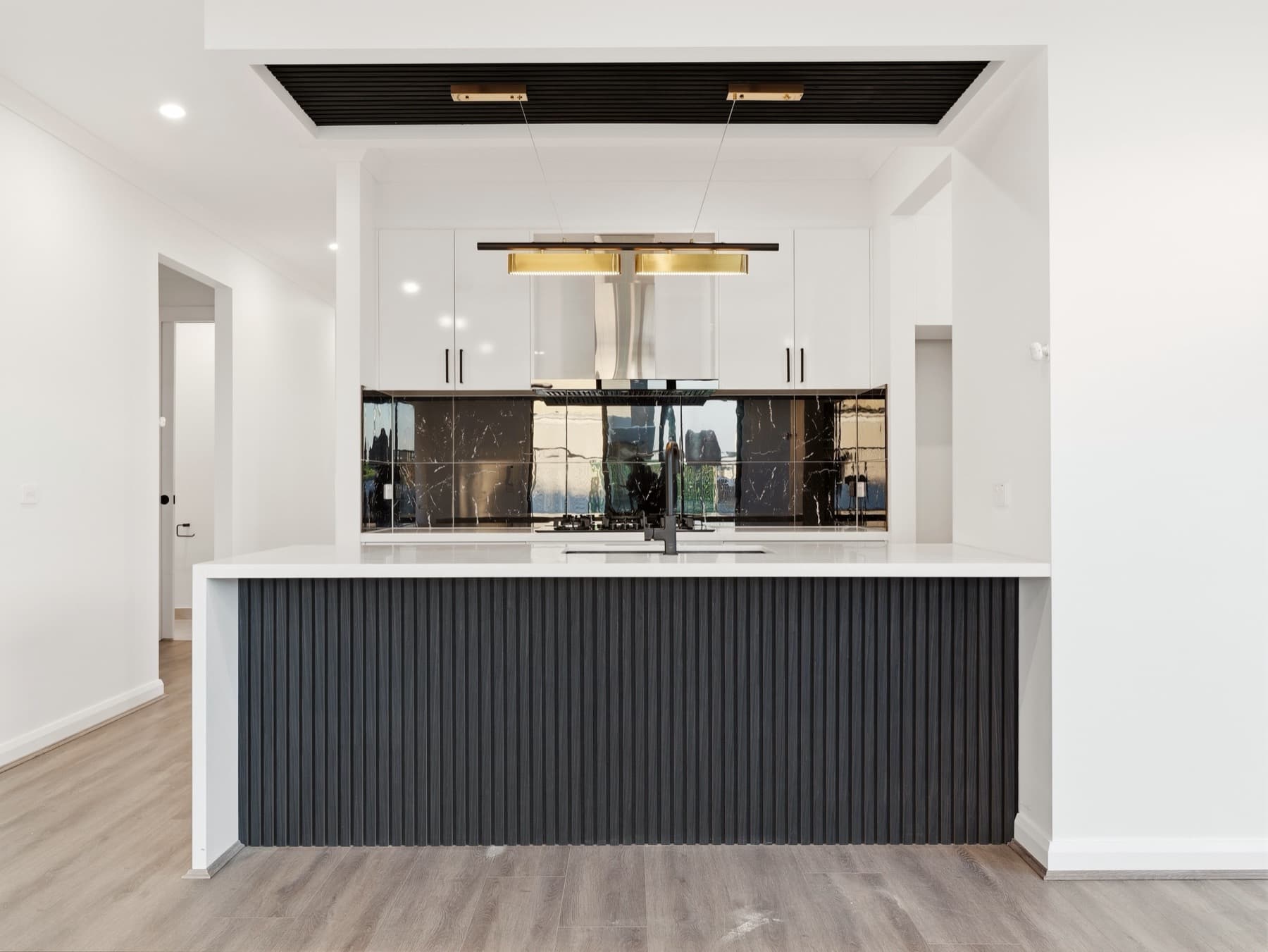 The kitchen island, fluted charcoal base beneath a black battened ceiling and brass pendant
