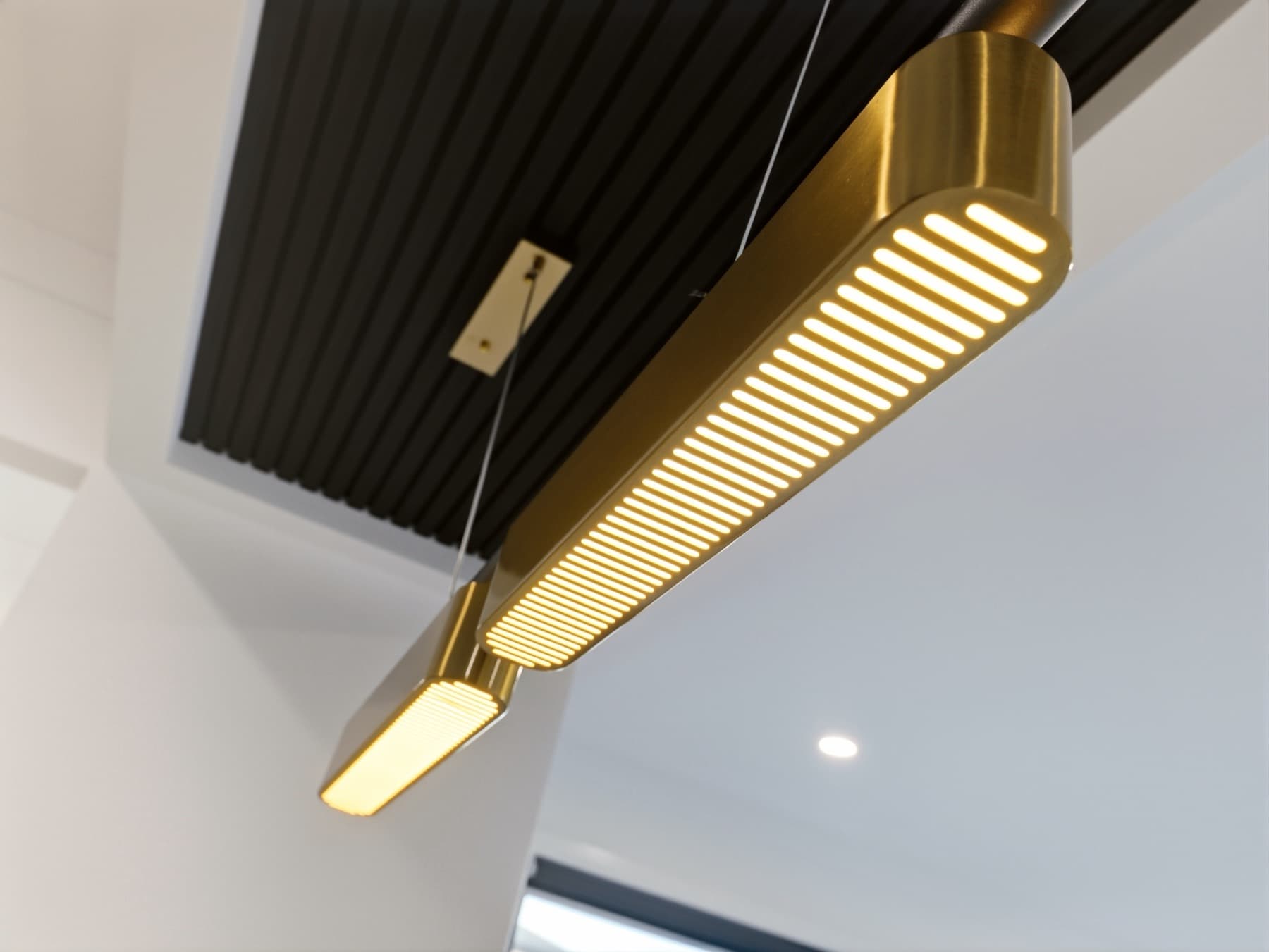 The brass pendant against the black battened ceiling