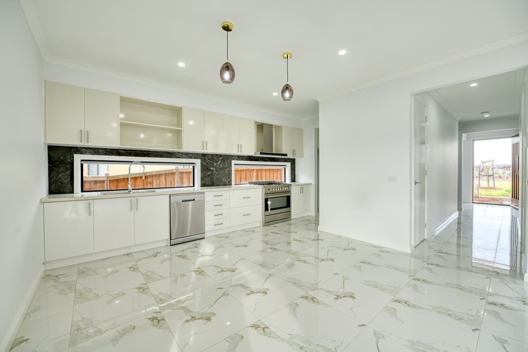 The kitchen, pendants over the bench and marble look floor